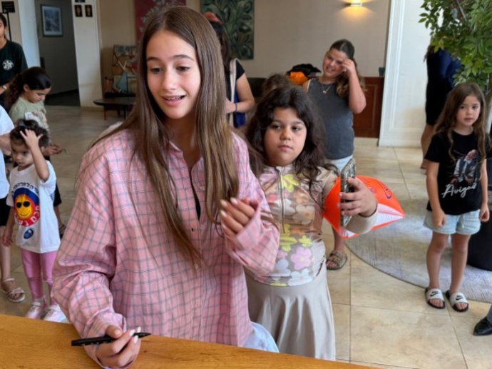 אביגיל ויסמן מחלקת חתימות לילדים בנופש. צילום: האגודה למלחמה בסרטן