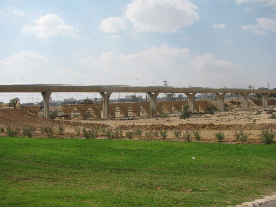 מדשאות פארק נחל באר שבע, ומעליהן הגשר החוצה את אפיק הנחל